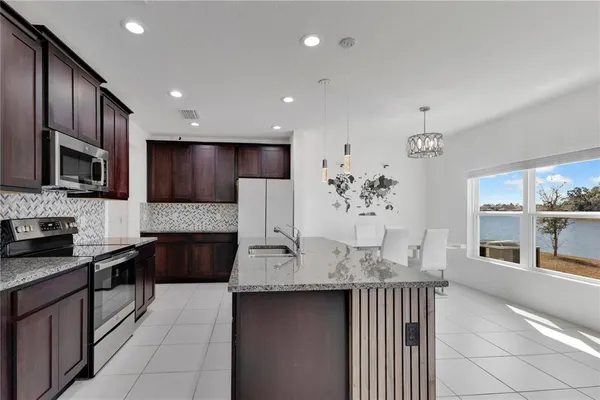 a kitchen with kitchen island granite countertop stainless steel appliances stove microwave refrigerator and cabinets