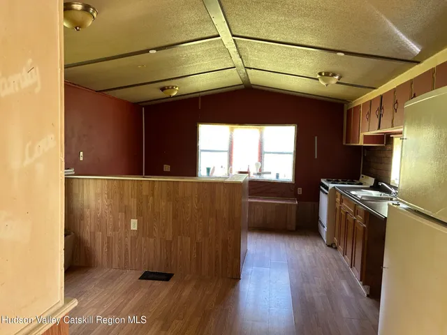 a kitchen with stainless steel appliances granite countertop a refrigerator a sink dishwasher a stove and white countertops with wooden floor