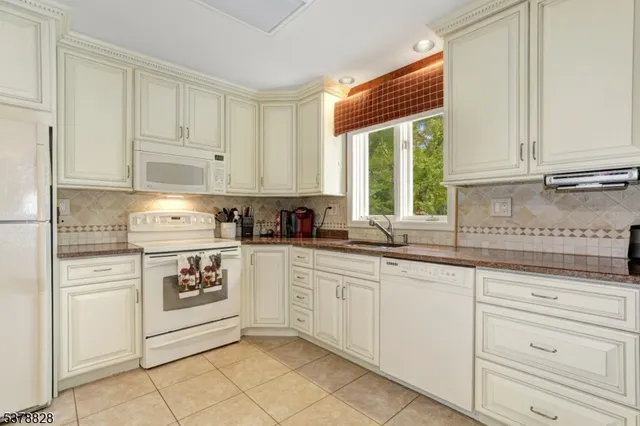 a kitchen with granite countertop white cabinets and white appliances