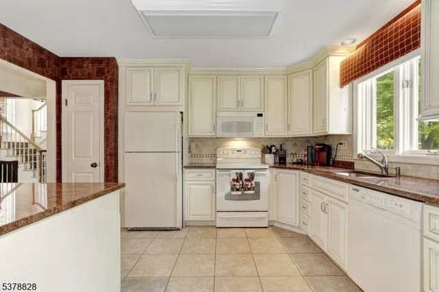 a kitchen with granite countertop white cabinets and white appliances