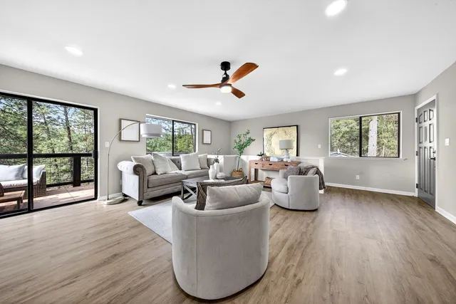 a living room with furniture large window and wooden floor