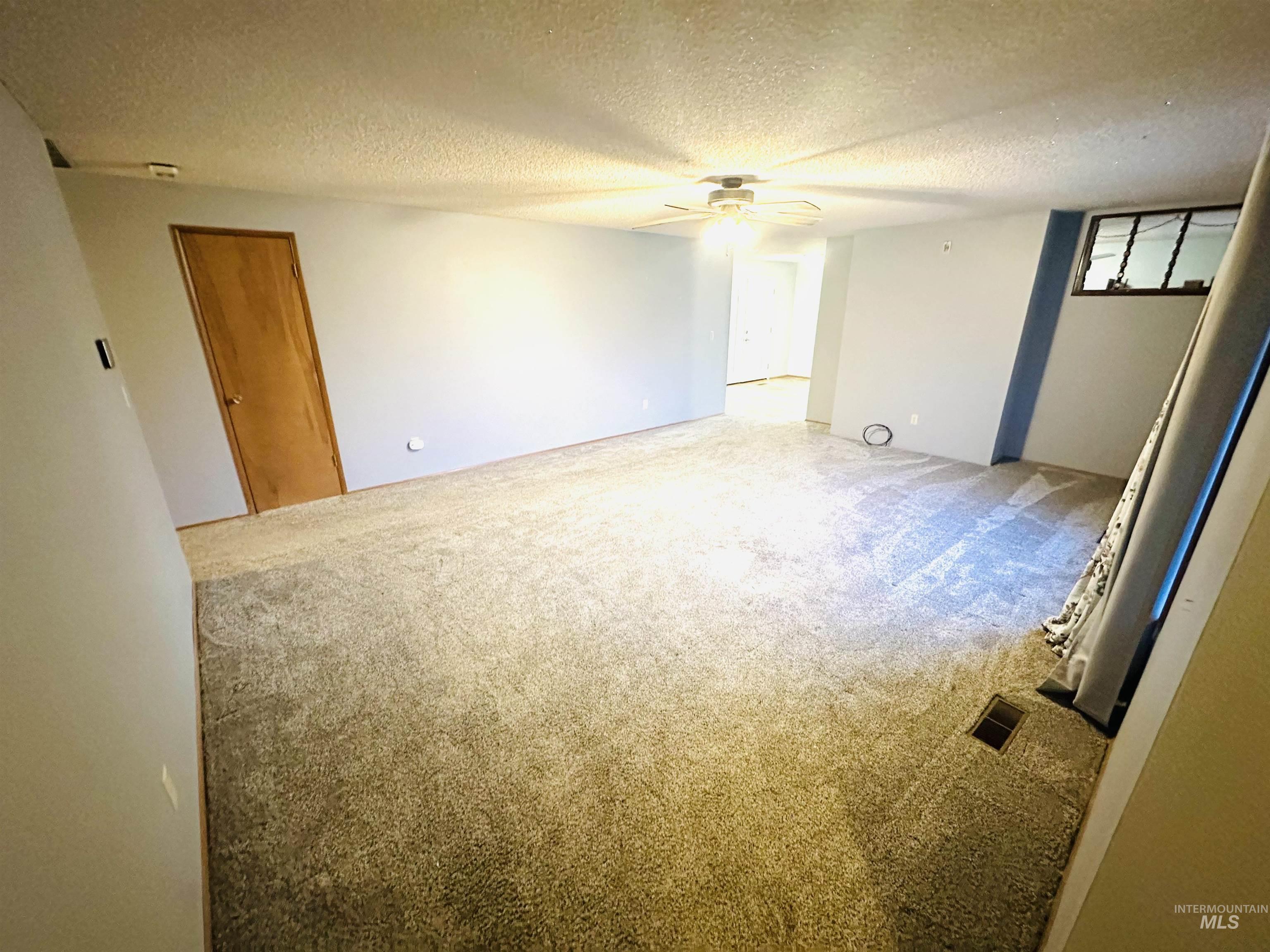 1111 West D Street Vale, OR 97918 - Photo 11 of 26 Unfurnished room with light colored carpet, a textured ceiling, and a ceiling fan