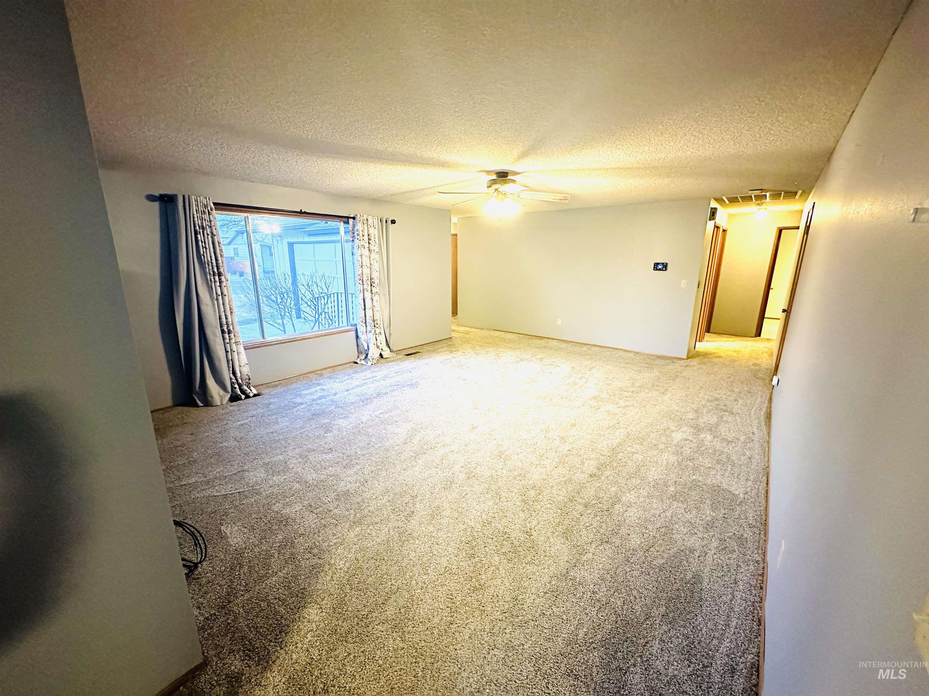 1111 West D Street Vale, OR 97918 - Photo 12 of 26 Spare room featuring a textured ceiling, a ceiling fan, and light colored carpet