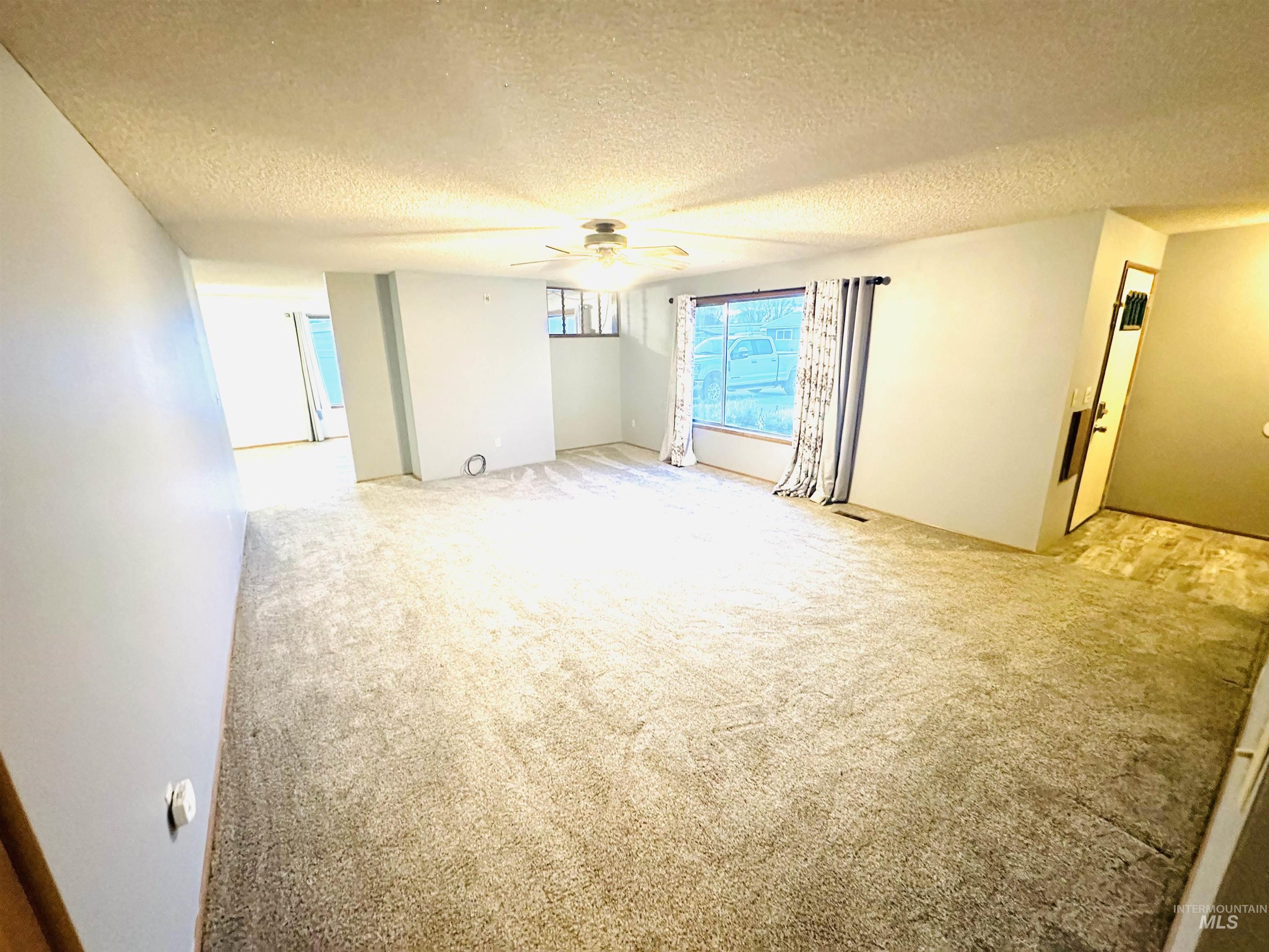 1111 West D Street Vale, OR 97918 - Photo 13 of 26 Spare room with a textured ceiling, light colored carpet, and ceiling fan
