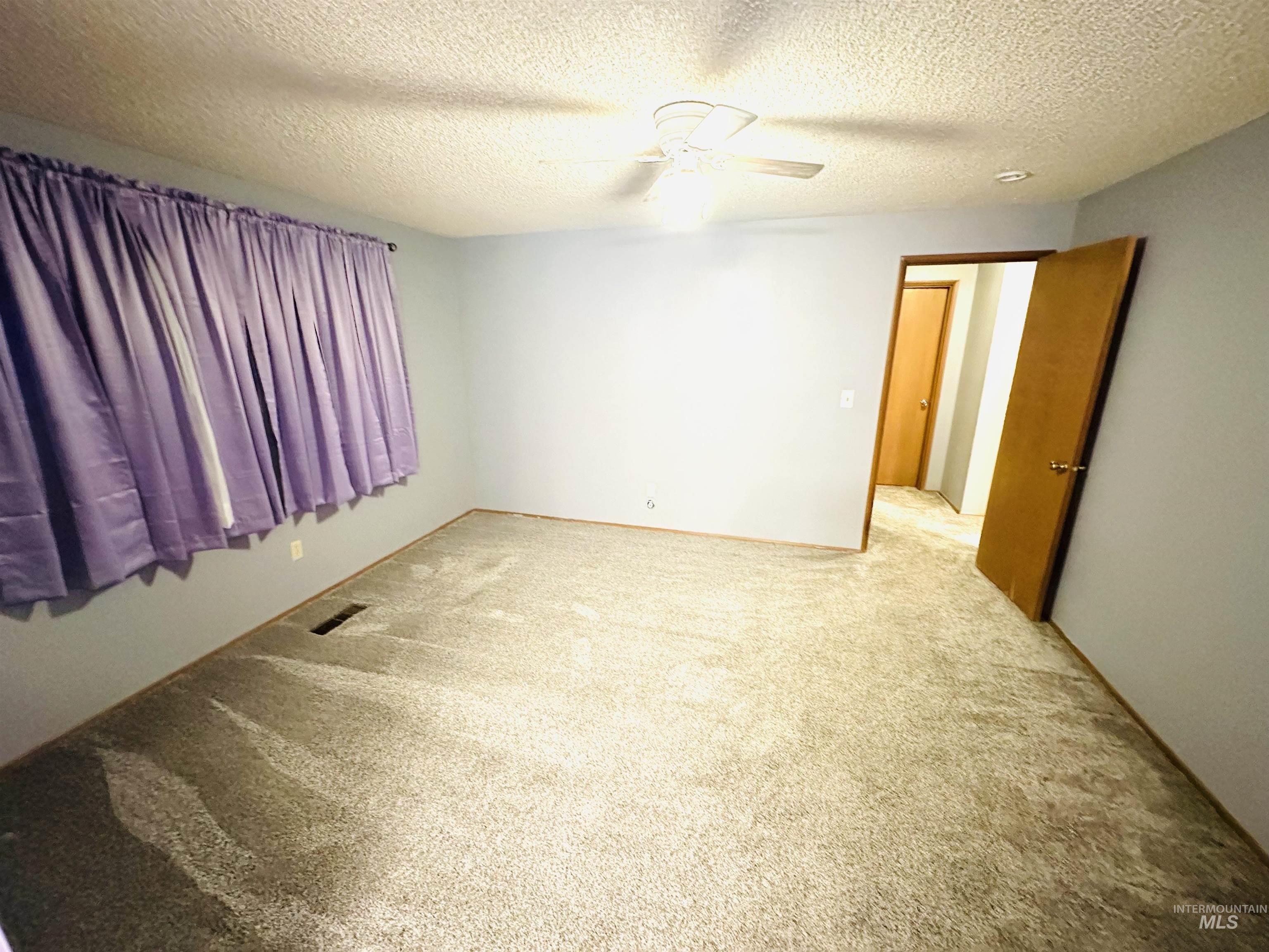 1111 West D Street Vale, OR 97918 - Photo 15 of 26 Empty room with a textured ceiling, light carpet, and ceiling fan