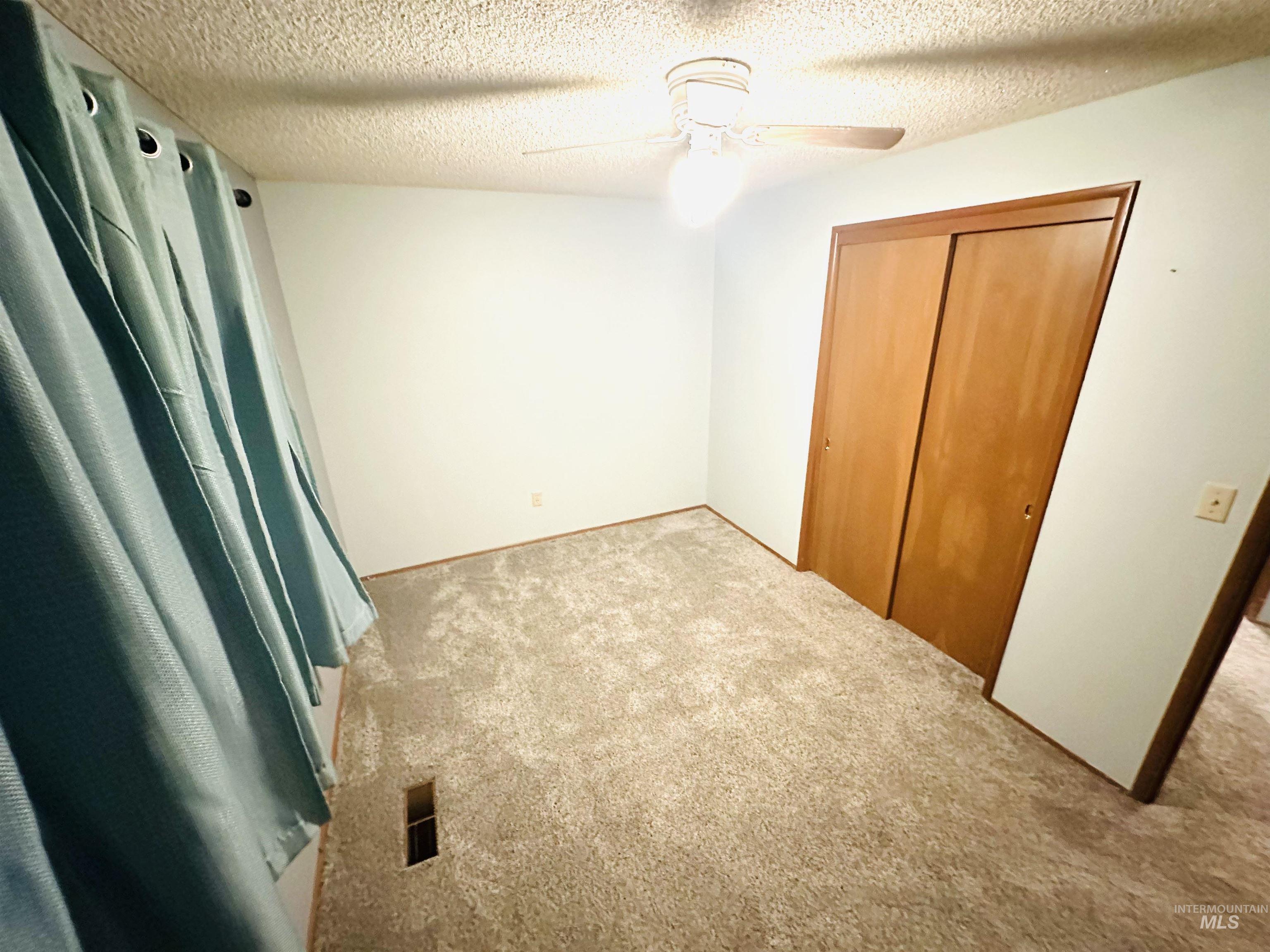 1111 West D Street Vale, OR 97918 - Photo 19 of 26 Unfurnished bedroom featuring a textured ceiling, carpet flooring, a ceiling fan, and a closet
