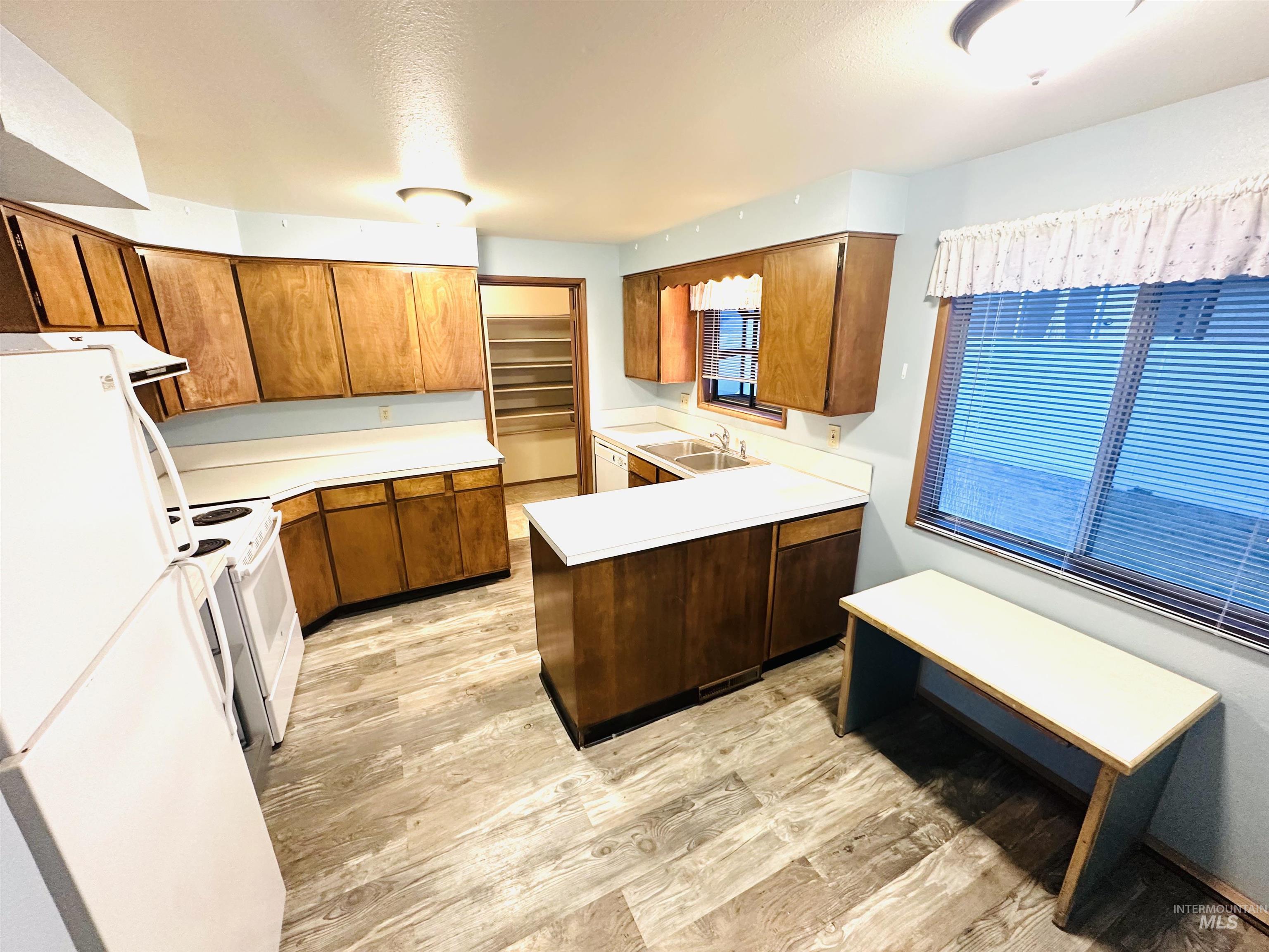 1111 West D Street Vale, OR 97918 - Photo 5 of 26 Kitchen featuring a peninsula, white appliances, light countertops, and wood finish cabinets