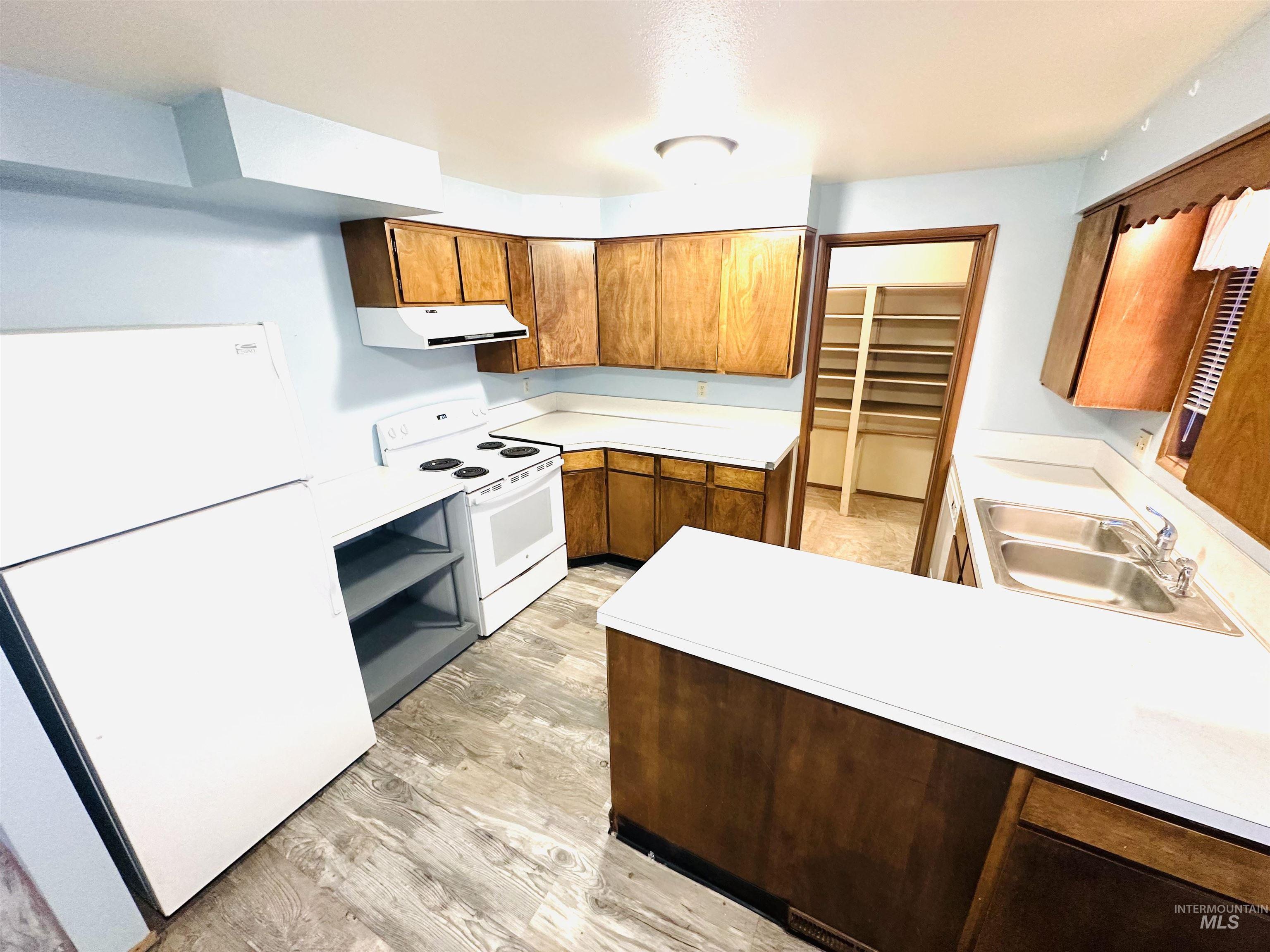 1111 West D Street Vale, OR 97918 - Photo 6 of 26 Kitchen featuring white appliances, wood finish cabinets, light countertops, a peninsula, and light wood finished floors