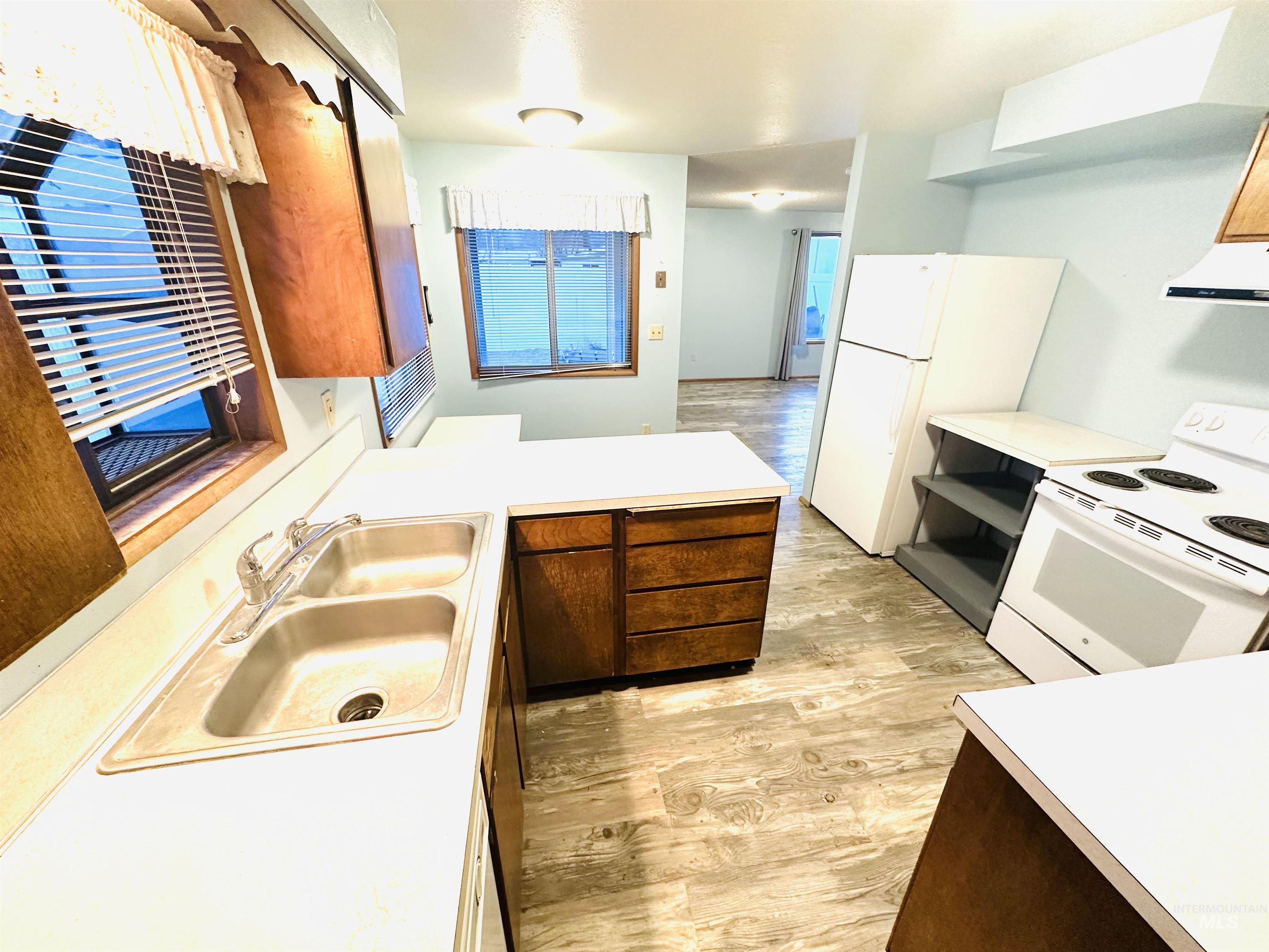 1111 West D Street Vale, OR 97918 - Photo 7 of 26 Kitchen featuring light wood-type flooring, white appliances, light countertops, and a peninsula