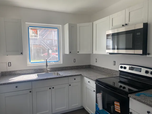 a kitchen with granite countertop cabinets stainless steel appliances and a window