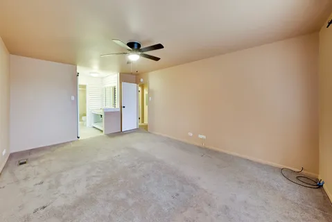 an empty room with a chandelier fan and windows