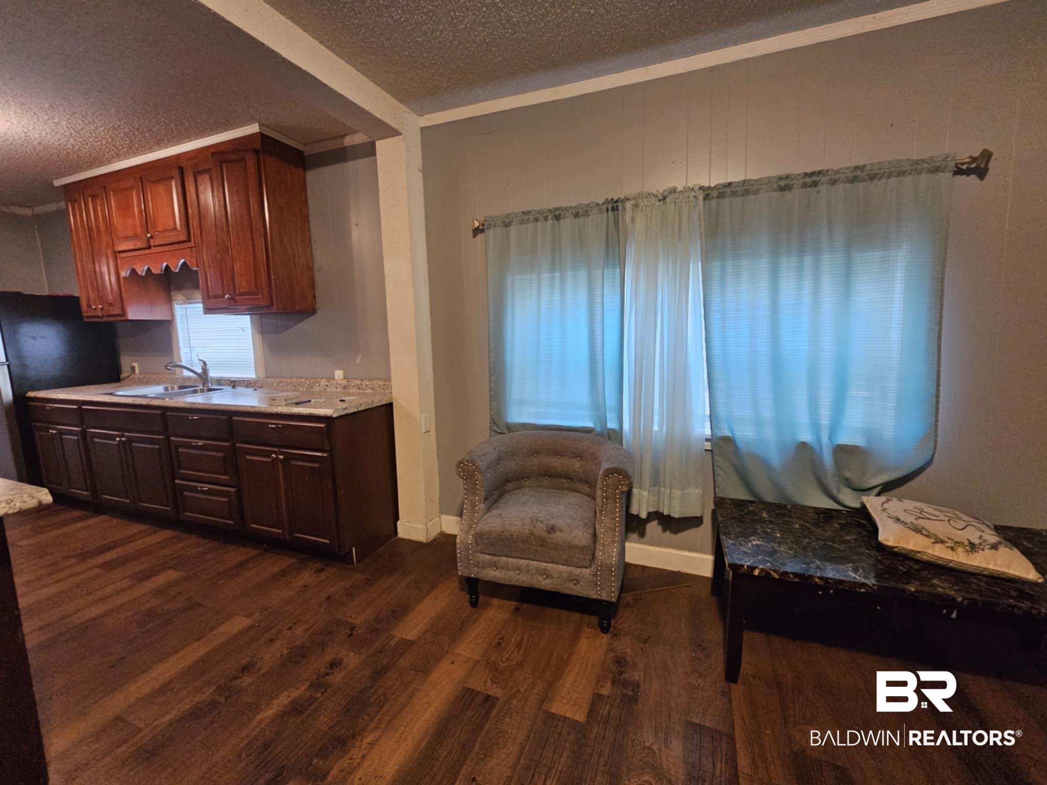 Sitting room featuring dark wood-style floors, crown molding, baseboards, and a textured ceiling