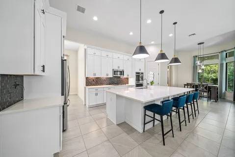 a kitchen with stainless steel appliances kitchen island granite countertop a sink a stove a dining table and chairs