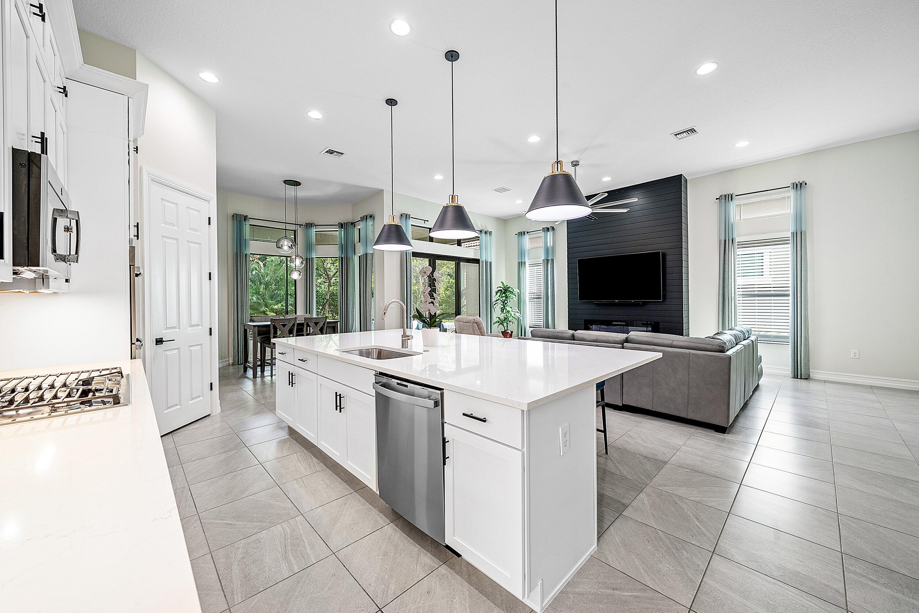9076 Leon Circle Parkland, FL 33076 - Photo 13 of 42 a large kitchen with stainless steel appliances kitchen island granite countertop a stove and a view of living room