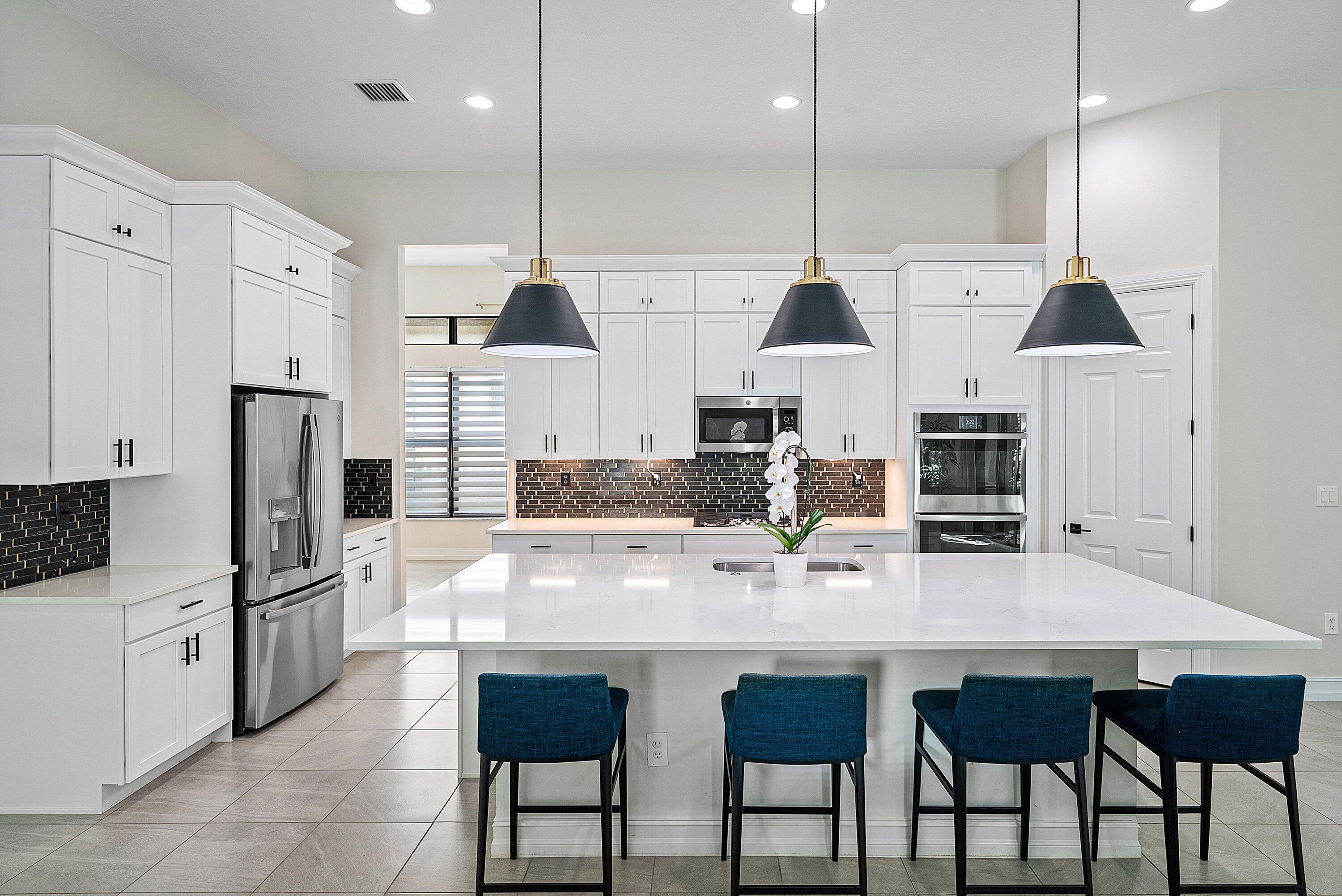 9076 Leon Circle Parkland, FL 33076 - Photo 15 of 42 a kitchen with stainless steel appliances kitchen island granite countertop a kitchen island and chairs in it