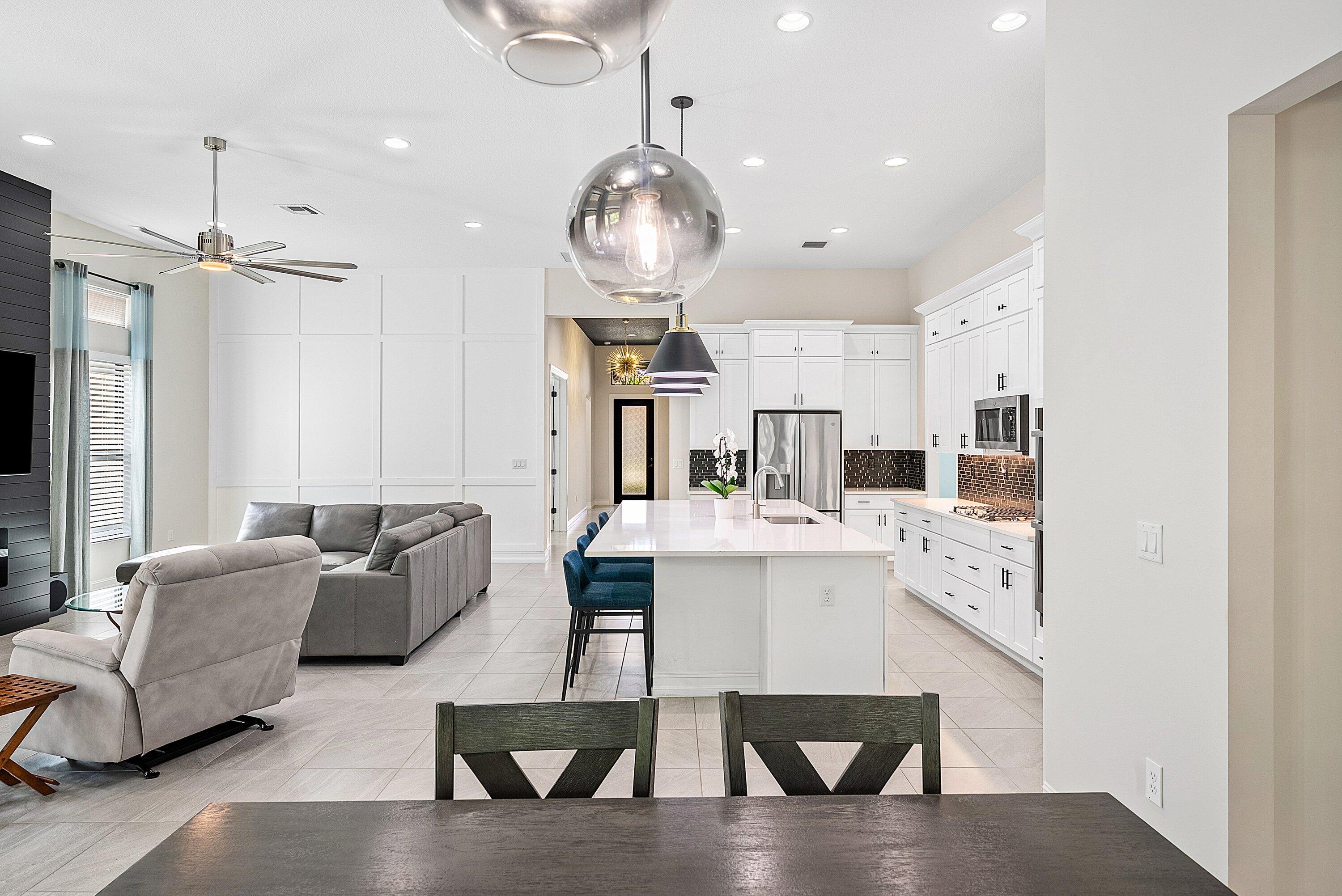 9076 Leon Circle Parkland, FL 33076 - Photo 17 of 42 a living room with furniture a chandelier and kitchen view