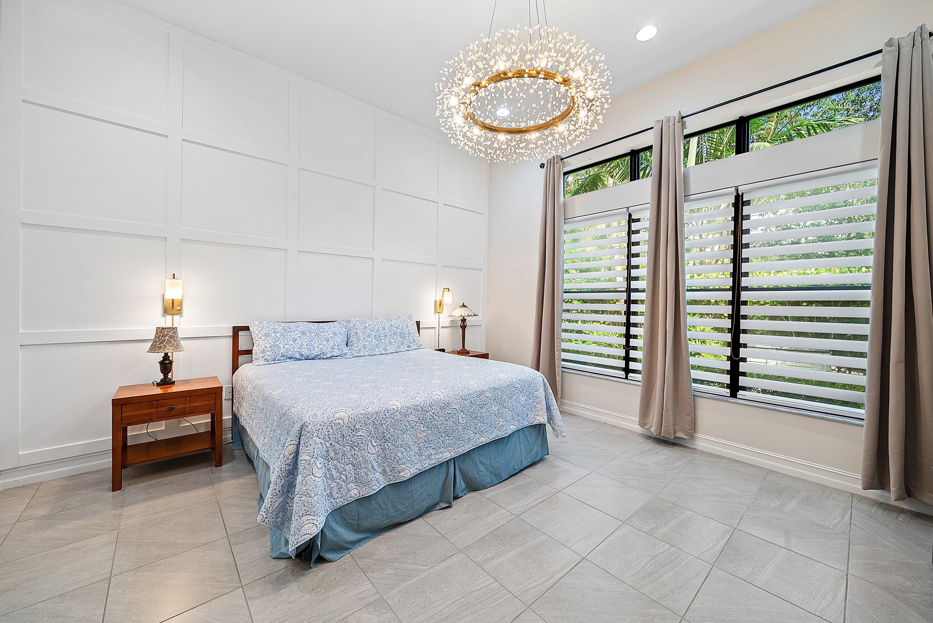 9076 Leon Circle Parkland, FL 33076 - Photo 25 of 42 a spacious bedroom with a bed and a chandelier