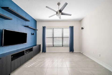 a living room with a flat screen tv and a ceiling fan