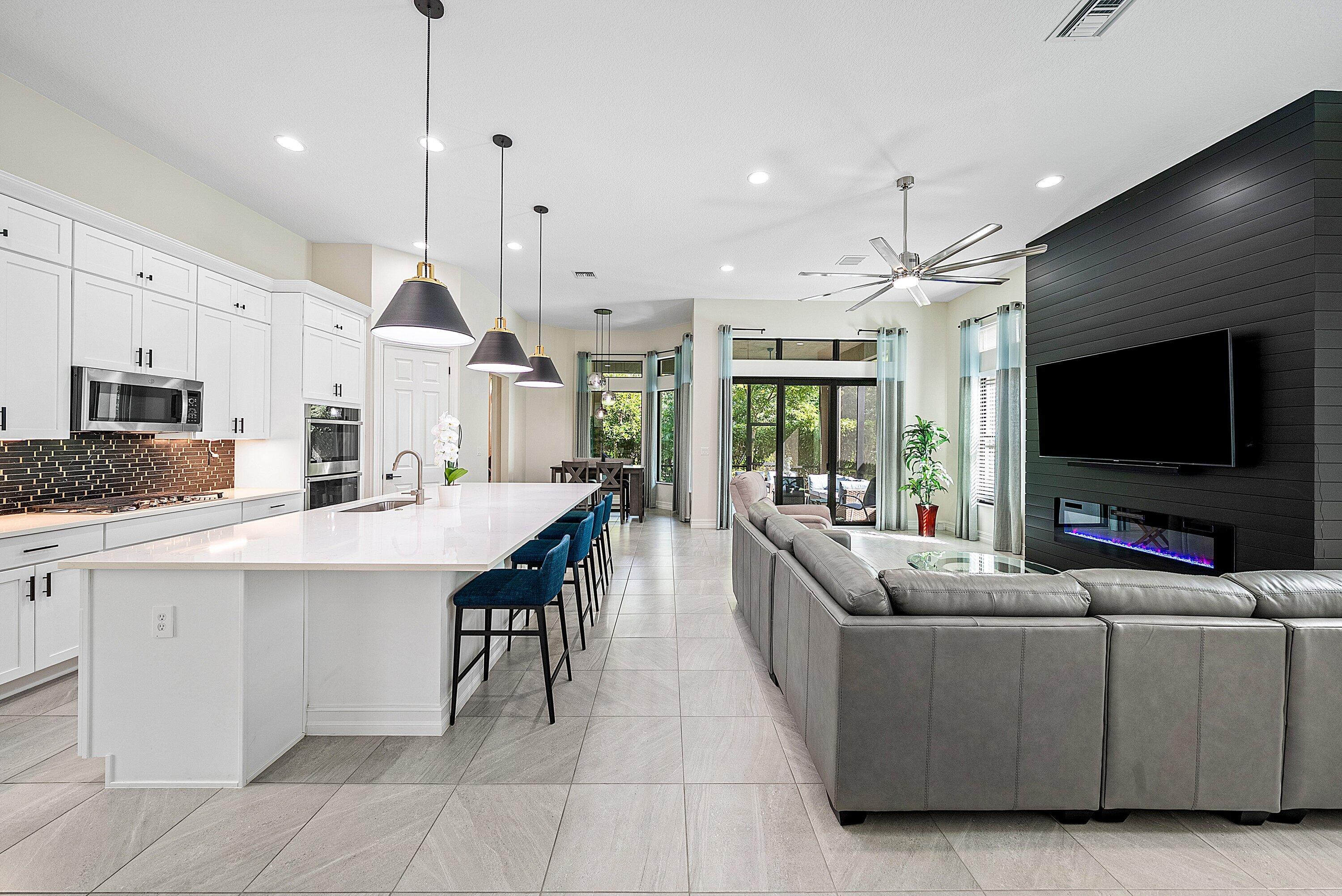 9076 Leon Circle Parkland, FL 33076 - Photo 10 of 42 a living room with stainless steel appliances kitchen island furniture and a flat screen tv
