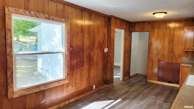 an empty room with wooden floor and windows with curtains view
