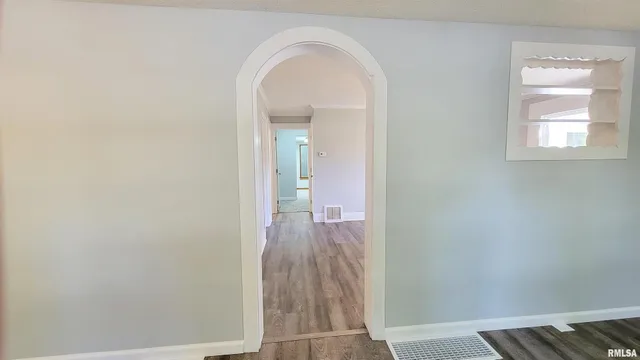 a view of a hallway with wooden floor and a livingroom