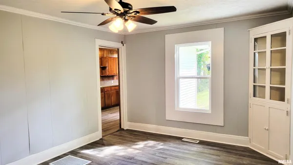 an empty room with wooden floor closet and windows