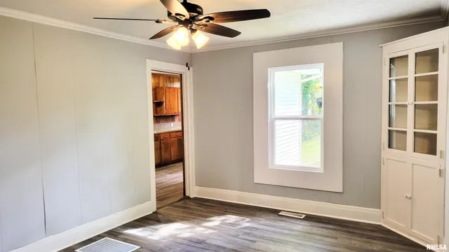 an empty room with wooden floor closet and windows