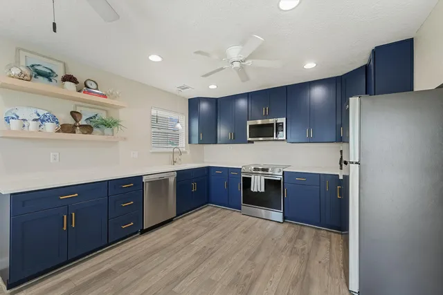 a kitchen with stainless steel appliances granite countertop wooden cabinets a refrigerator a sink and wooden floor