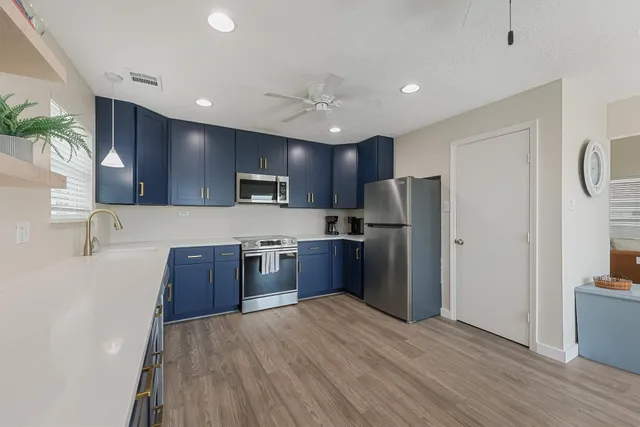 a kitchen with stainless steel appliances granite countertop a refrigerator a sink dishwasher a stove top oven a refrigerator with wooden floor