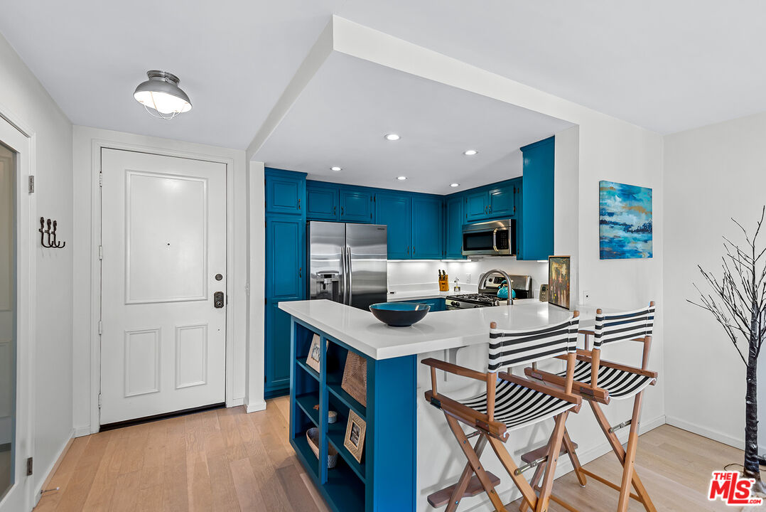 8600 Tuscany Avenue, Unit 419 Playa del Rey, CA 90293 - Photo 4 of 35 a open kitchen with stainless steel appliances granite countertop a stove top oven a dining table and chairs with wooden floor