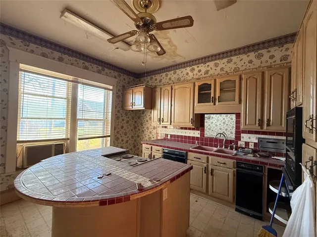 a kitchen with a stove a sink a window and cabinets