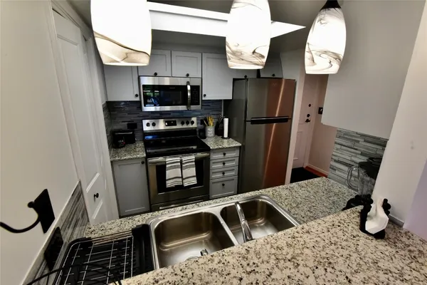 a kitchen with granite countertop a stove and refrigerator