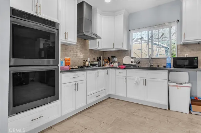a kitchen with stainless steel appliances granite countertop a refrigerator a sink a window and white cabinets