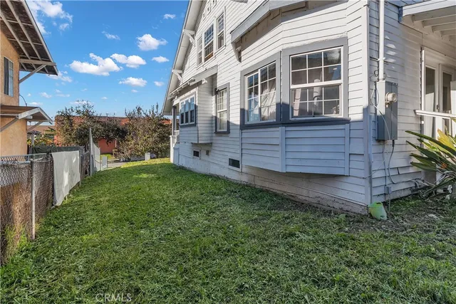a view of a house with backyard and wooden fence