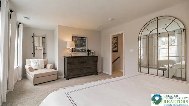 a spacious bedroom with a bed a couch and large window