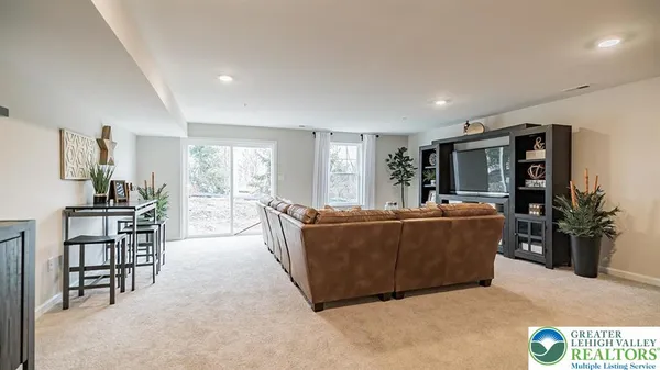 a living room with furniture a flat screen tv and a refrigerator