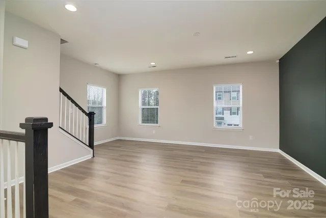 a view of empty room with wooden floor and windows