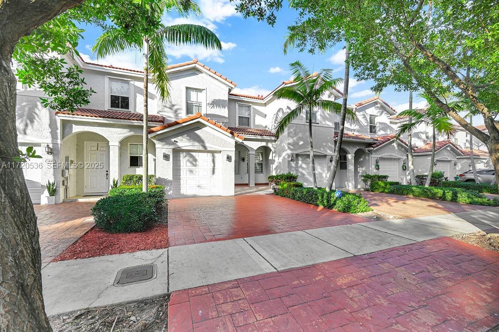 1007 Northeast 208th Street, Unit 1007 Miami, FL 33179 - Photo 35 of 68 a front view of a house with garden and parking