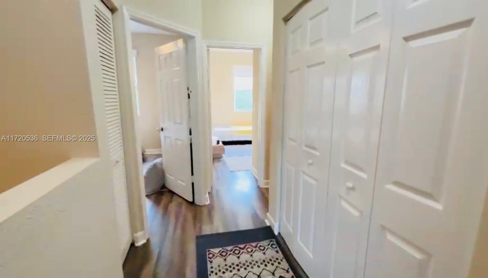 1007 Northeast 208th Street, Unit 1007 Miami, FL 33179 - Photo 47 of 68 a view of a hallway with wooden floor and a bathroom