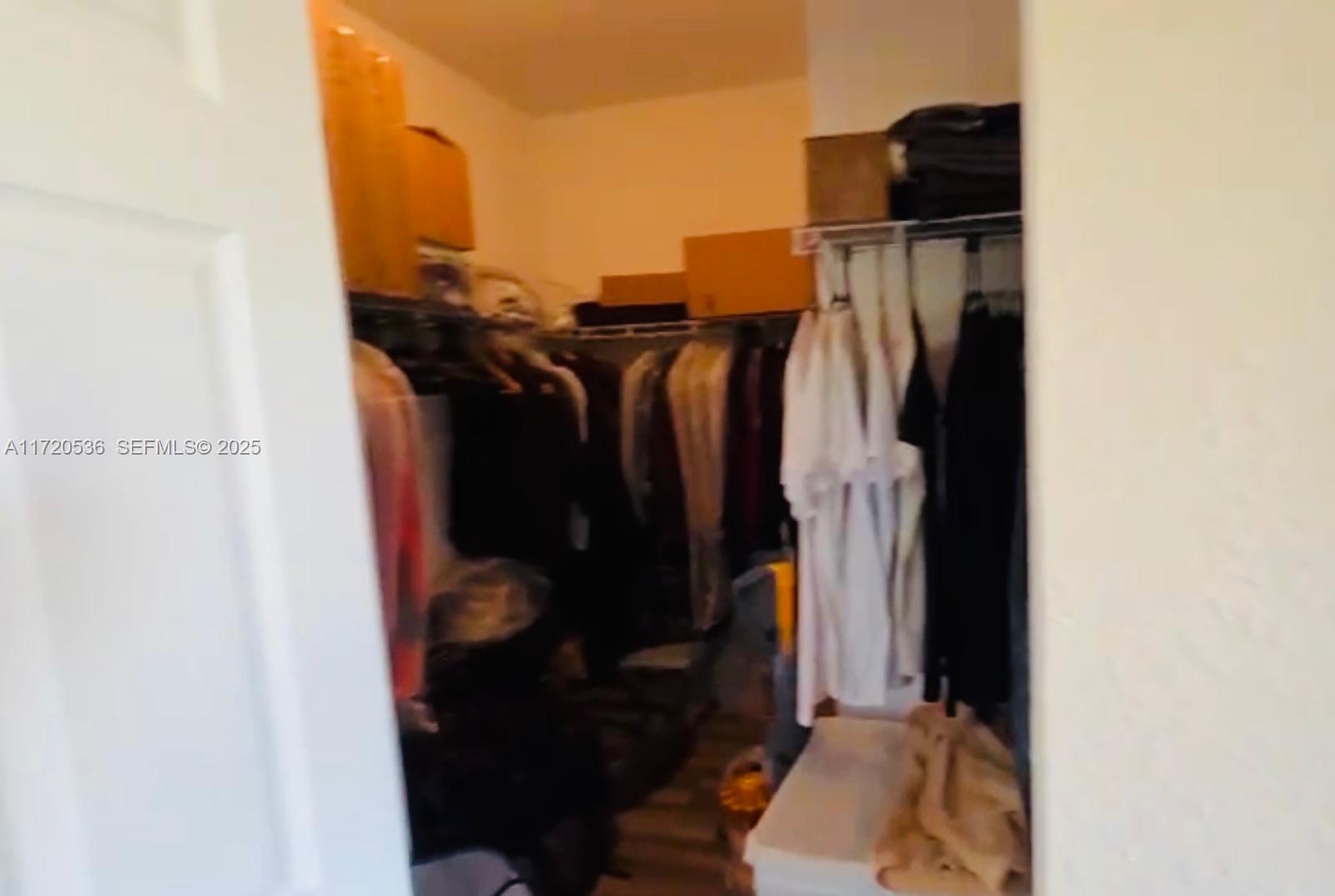 1007 Northeast 208th Street, Unit 1007 Miami, FL 33179 - Photo 54 of 68 a view of walk in closet with clothes and shoes
