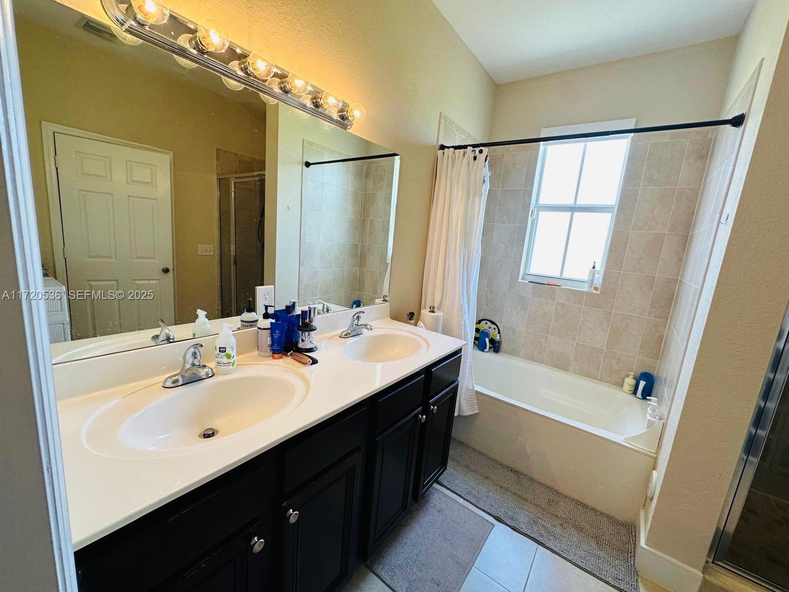 1007 Northeast 208th Street, Unit 1007 Miami, FL 33179 - Photo 56 of 68 a bathroom with a double vanity sink a mirror and a bathtub