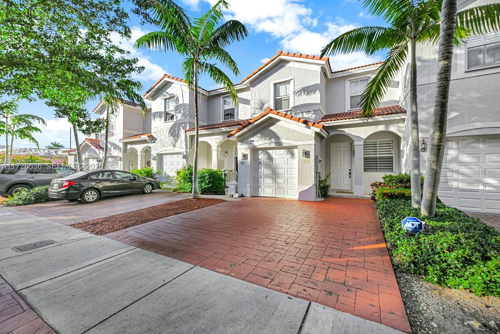 1007 Northeast 208th Street, Unit 1007 Miami, FL 33179 - Photo 8 of 68 a view of a white house with a small yard and palm trees