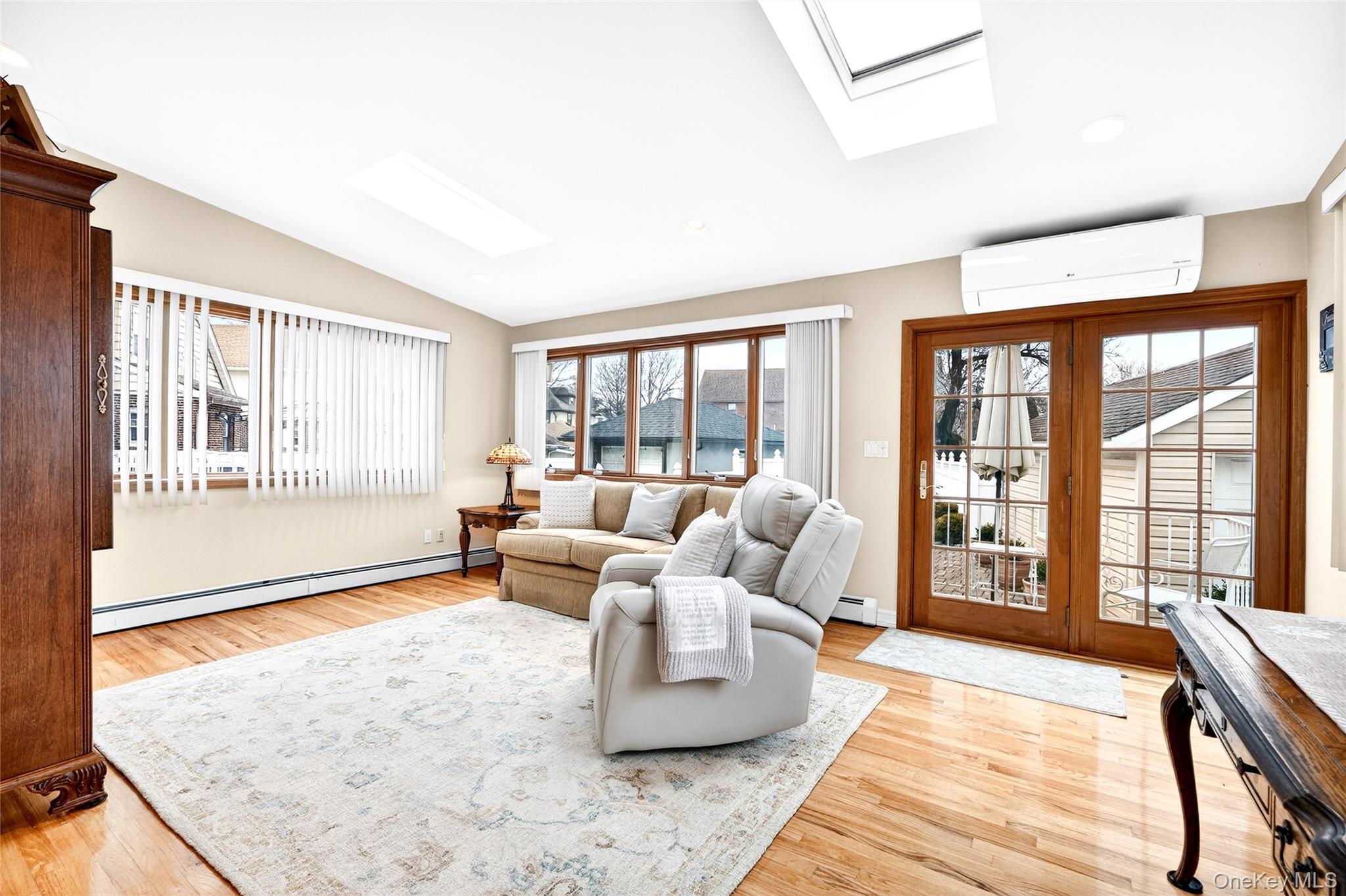 3334 Country Club Road Bronx, NY 10465 - Photo 21 of 49 Living area with a skylight, a baseboard radiator, lofted ceiling, a wall mounted AC, and plenty of natural light