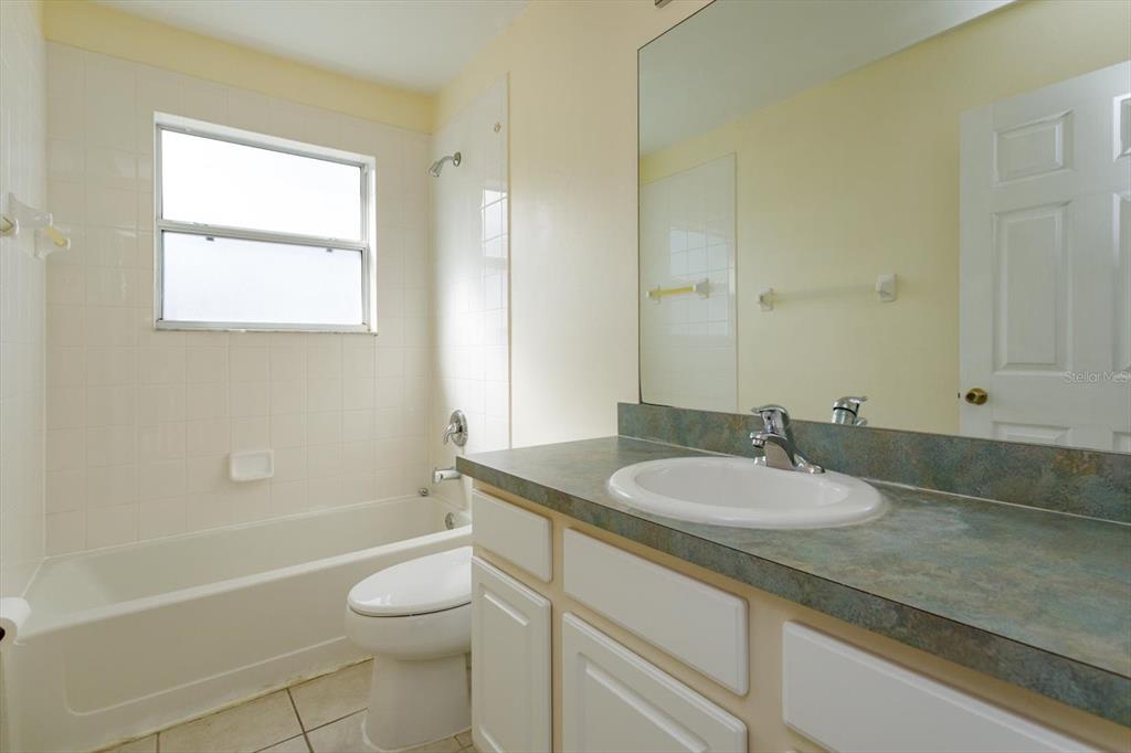 2833 Kokomo Loop Haines City, FL 33844 - Photo 21 of 30 a bathroom with a granite countertop sink toilet a large mirror a bathtub and shower