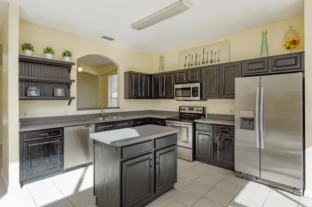 a kitchen with kitchen island granite countertop stainless steel appliances a sink stove refrigerator and a window