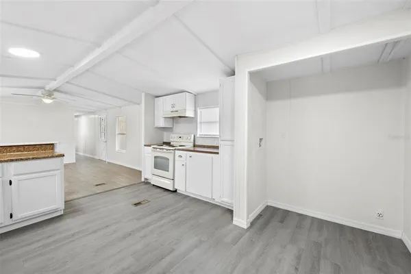 a kitchen with white cabinets and wooden floor
