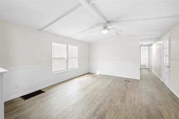an empty room with wooden floor fan and windows