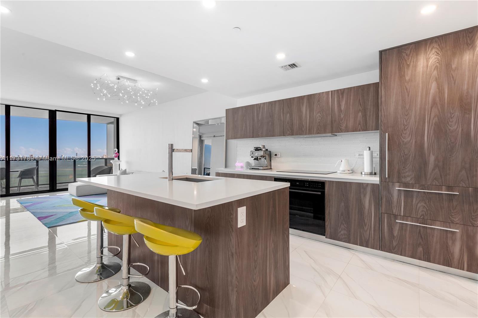 3131 Northeast 7th Avenue, Unit 1902 Miami, FL 33137 - Photo 19 of 20 a kitchen with kitchen island granite countertop wooden cabinets and counter space