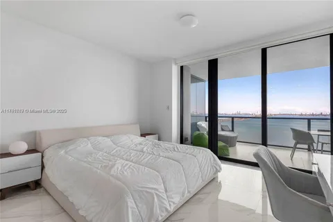 a bedroom with a bed and a large window with balcony view