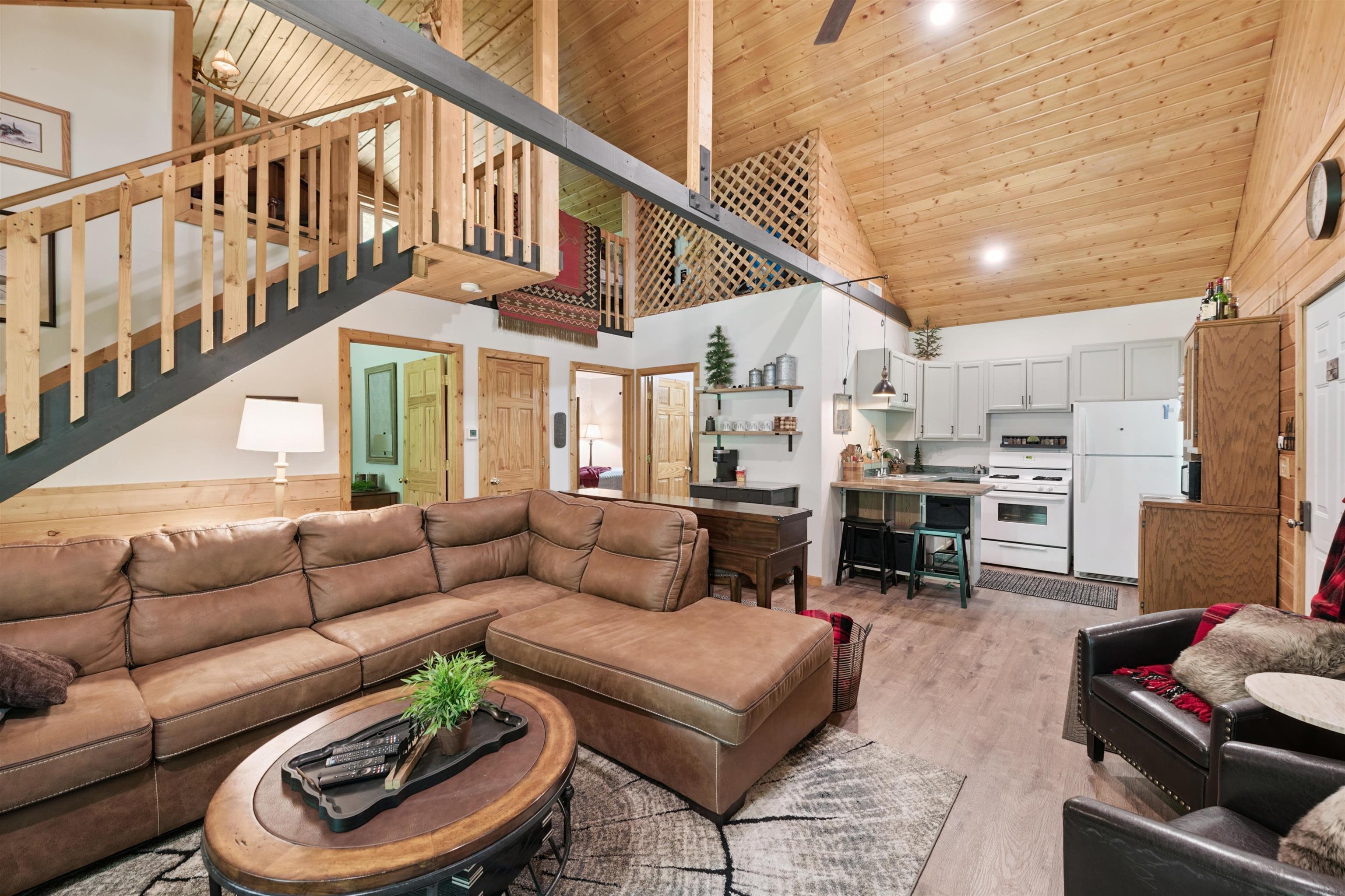 Living area featuring high vaulted ceiling, stairway, light wood finished floors, and wood ceiling